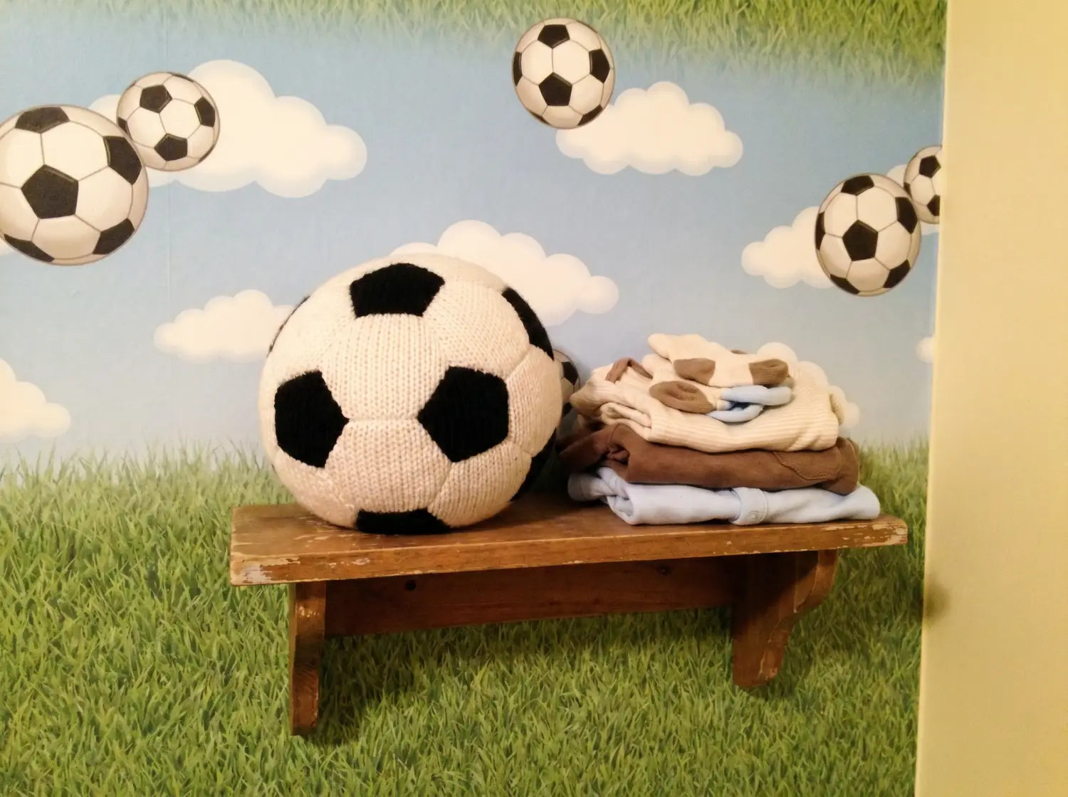 Papier peint panoramique terrain de football derrière un lit à barreaux en bois dans une chambre de bébé