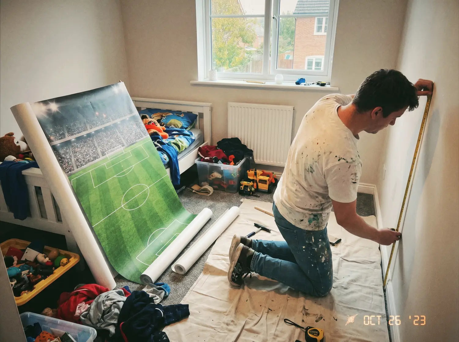 Chambre d'ado avec papier peint panoramique terrain de foot derrière le bureau