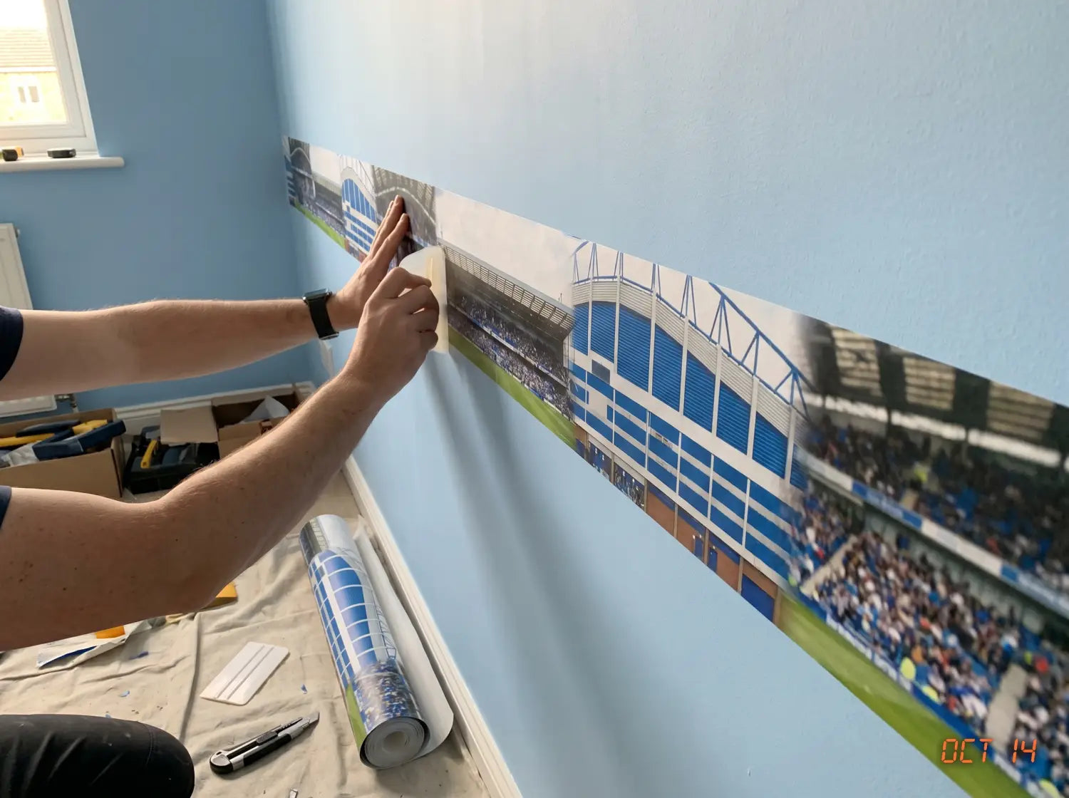 Pose d'un lé de papier peint panoramique football sur un mur de chambre