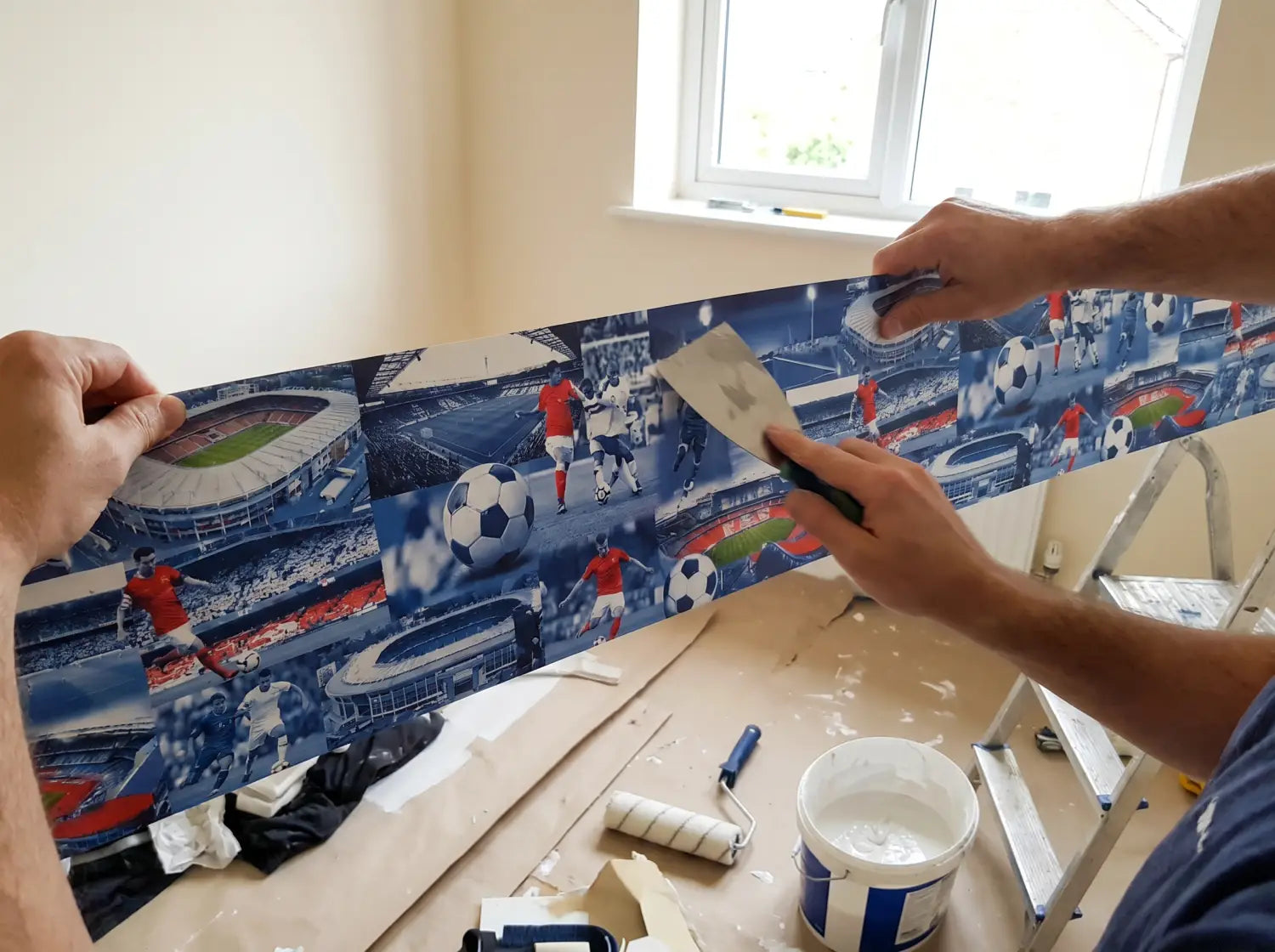 Parent posant un lé de papier peint bleu blanc rouge équipe de France dans une chambre d'enfant