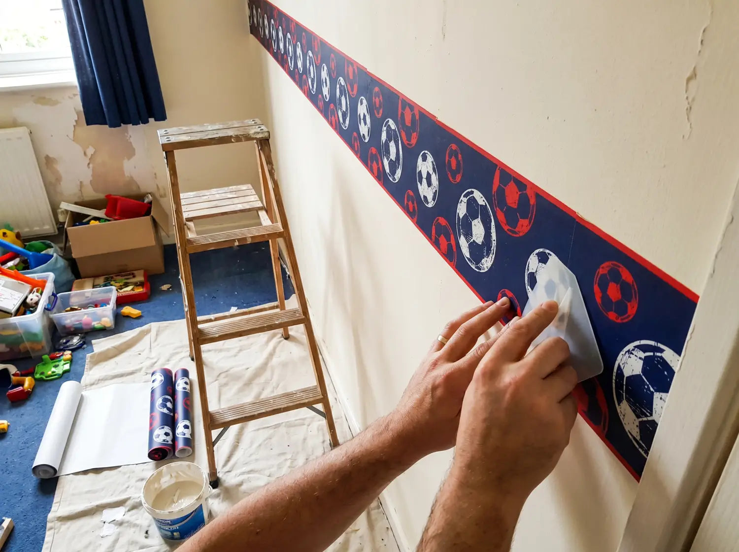 Pose d'un lé de papier peint football dans une chambre d'enfant