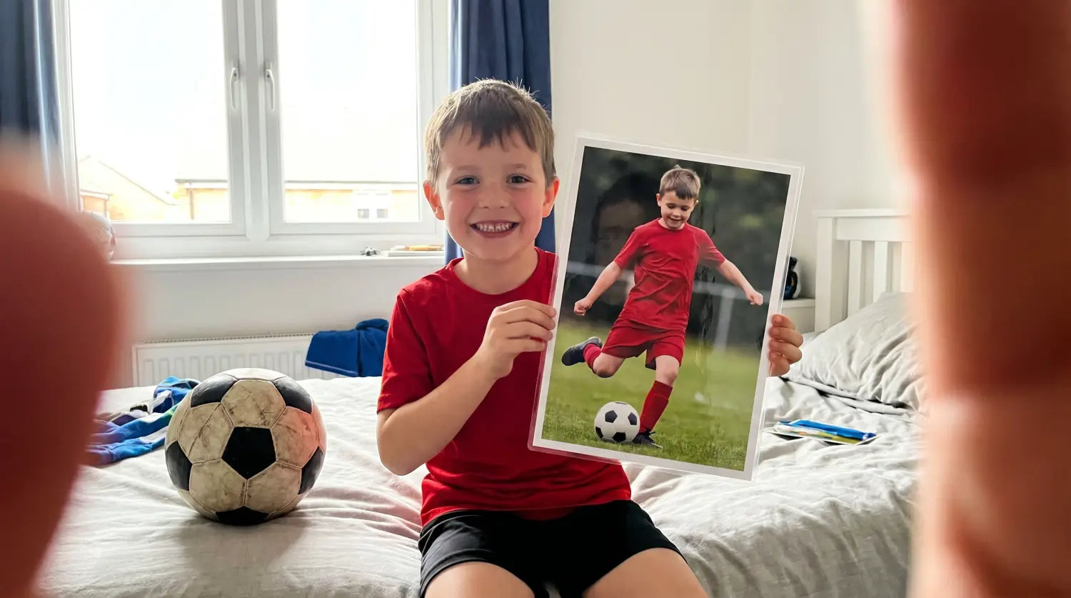 Enfant fier tenant sa carte de joueur de foot personnalisée avec sa photo dans sa chambre