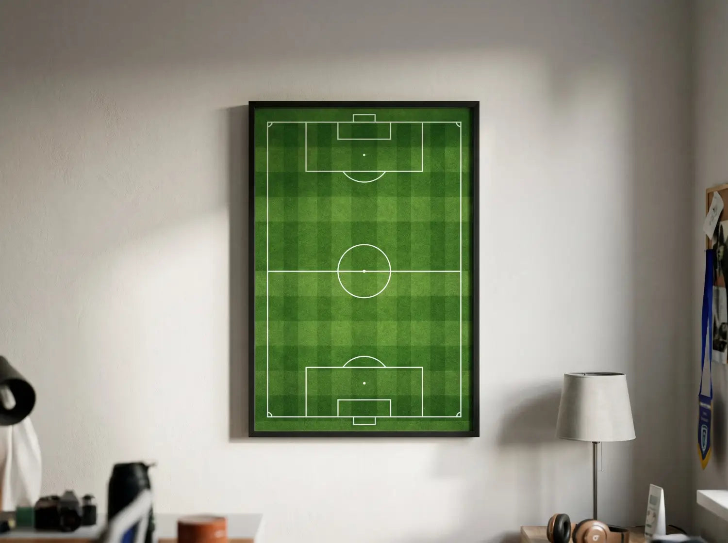 Gros plan d'une affiche de terrain de football vu du dessus encadrée sur un mur clair