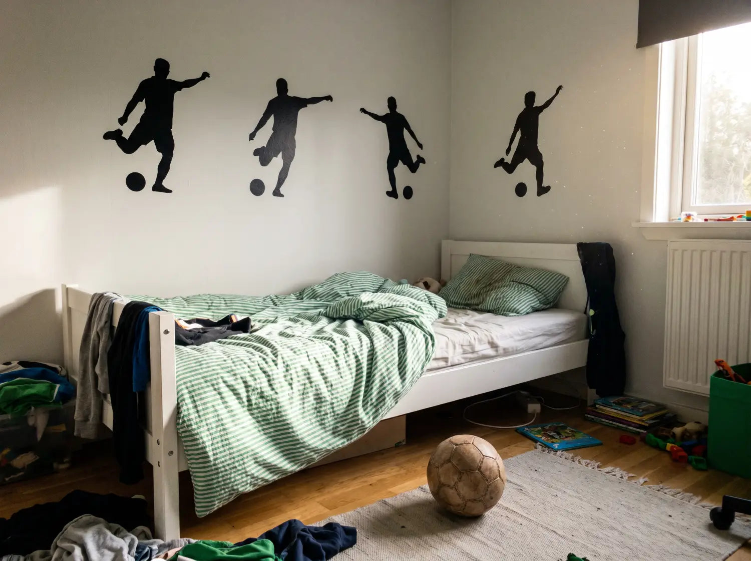 Chambre de garçon décorée de stickers muraux silhouette de footballeur au-dessus du lit
