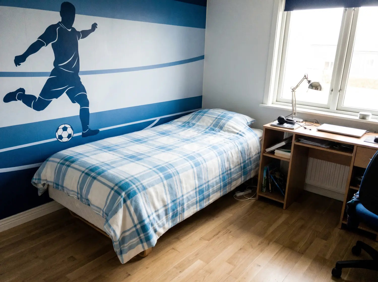 Chambre d'ado avec papier peint football bleu ciel derrière la tête de lit