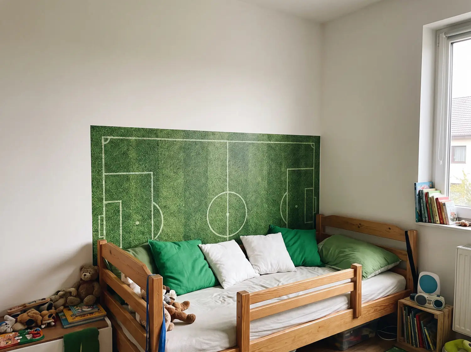 Lé de papier peint football posé derrière la tête de lit d'une chambre d'enfant